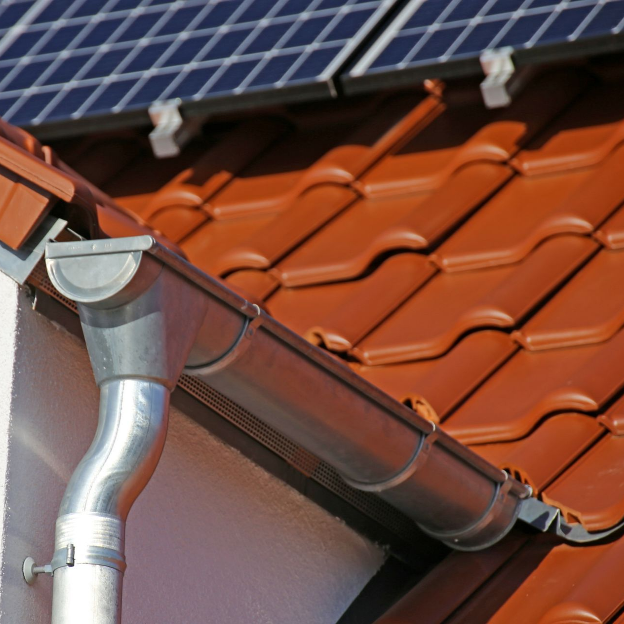 Gros plan sur le toit d'une maison avec une gouttière argentée.