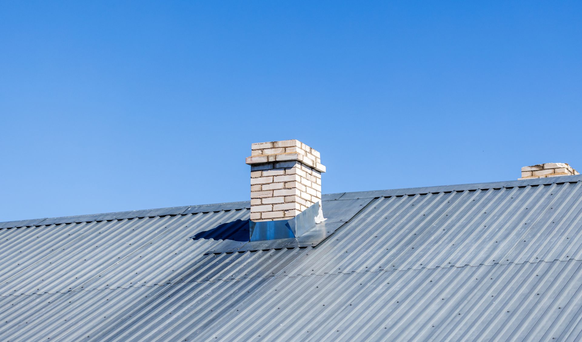 Cheminée en briques sur un toit en tôle ondulée.