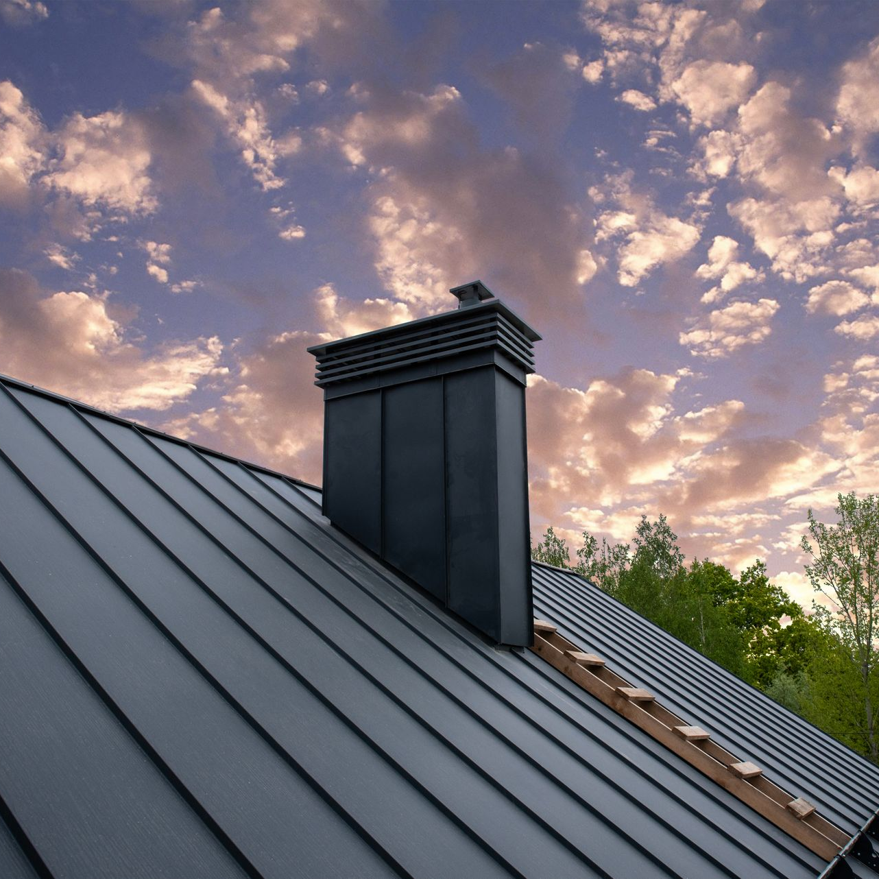 Toit en métal noir avec cheminée sur fond de ciel nuageux.