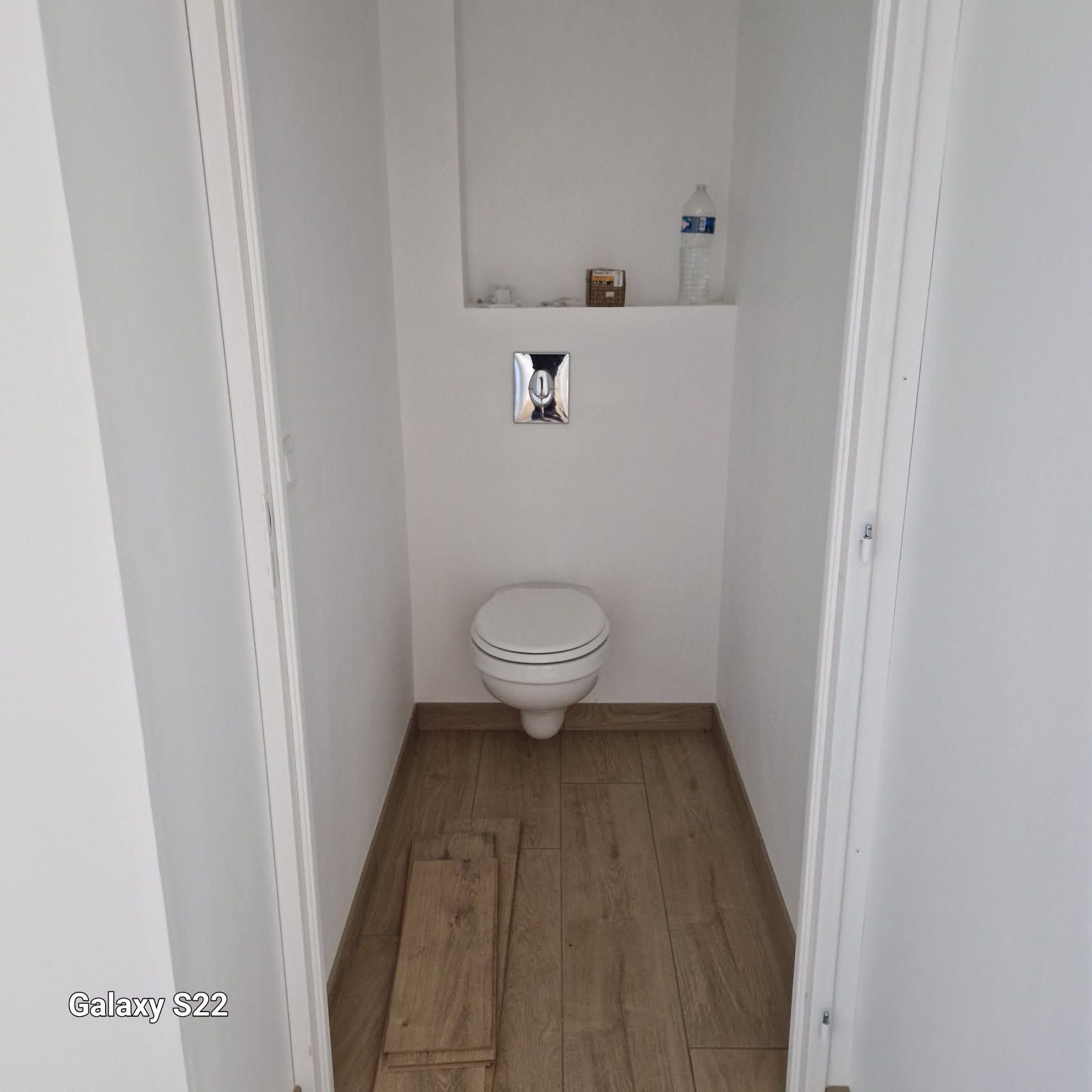 Divers éléments de robinetterie et des outils sur le sol d'une salle de bains