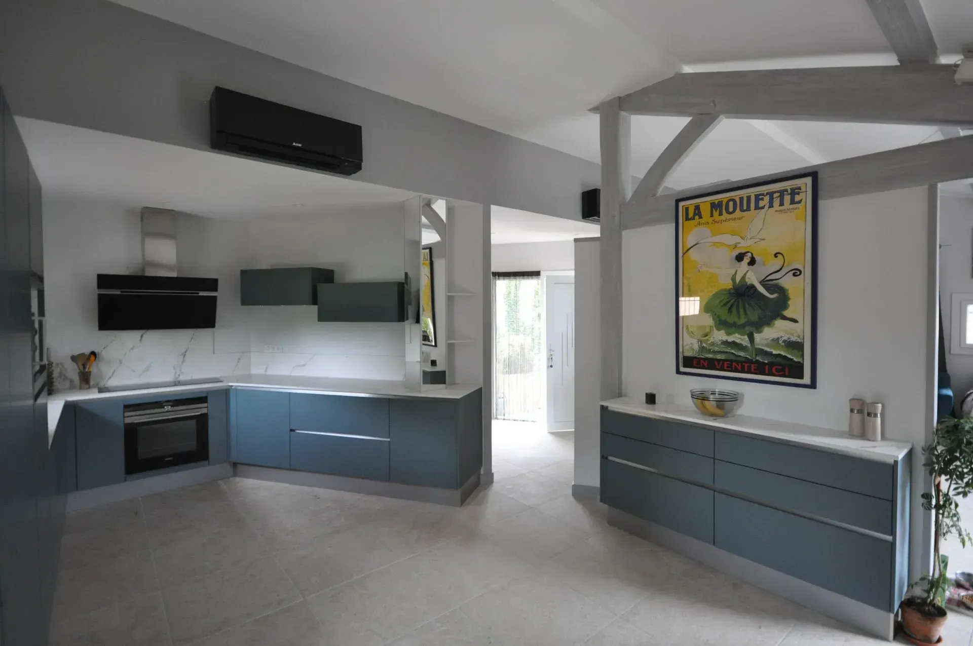 Cuisine moderne avec placards bleus, comptoirs en marbre et une affiche vintage.