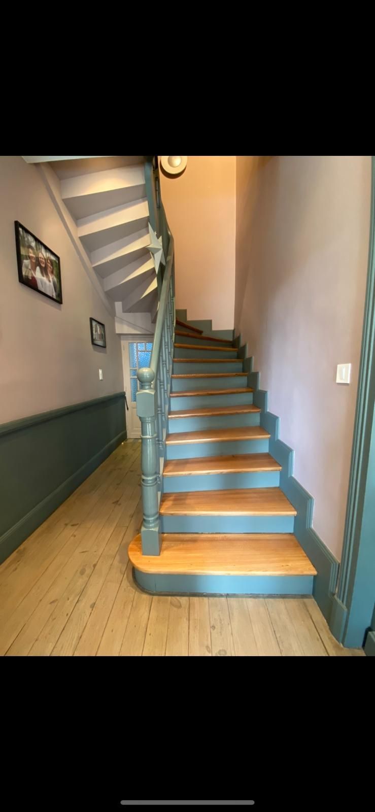 Escalier en bois dans une maison avec parquet. Finitions vertes. Murs roses.