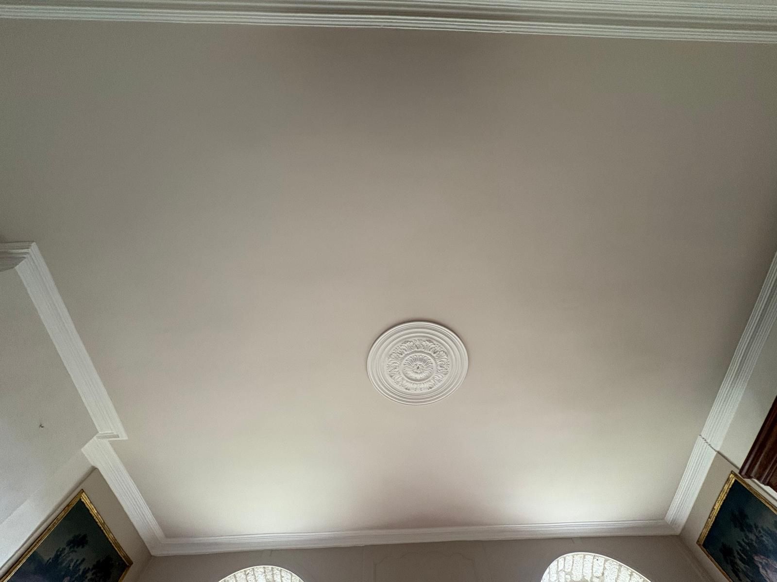 Plafond beige avec moulures blanches et médaillon décoratif.
