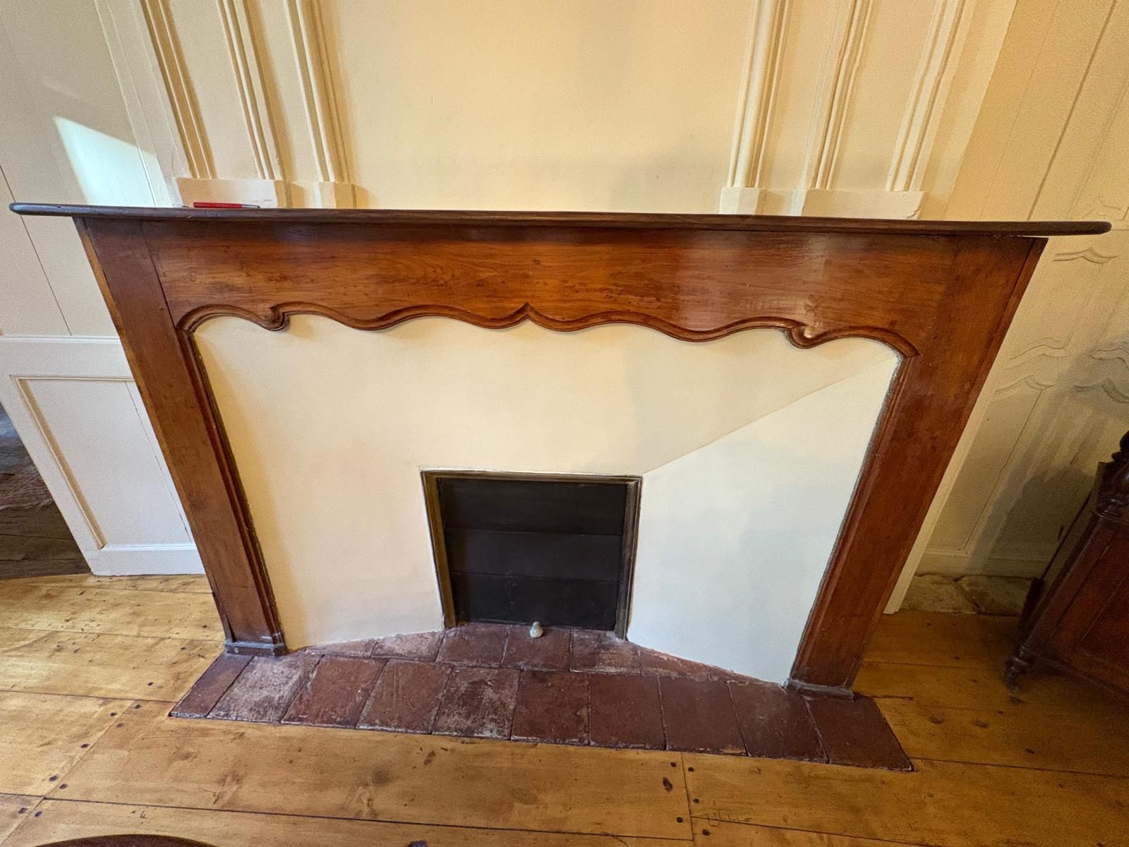 Cheminée en bois avec entourage beige, foyer et ouverture foncés.