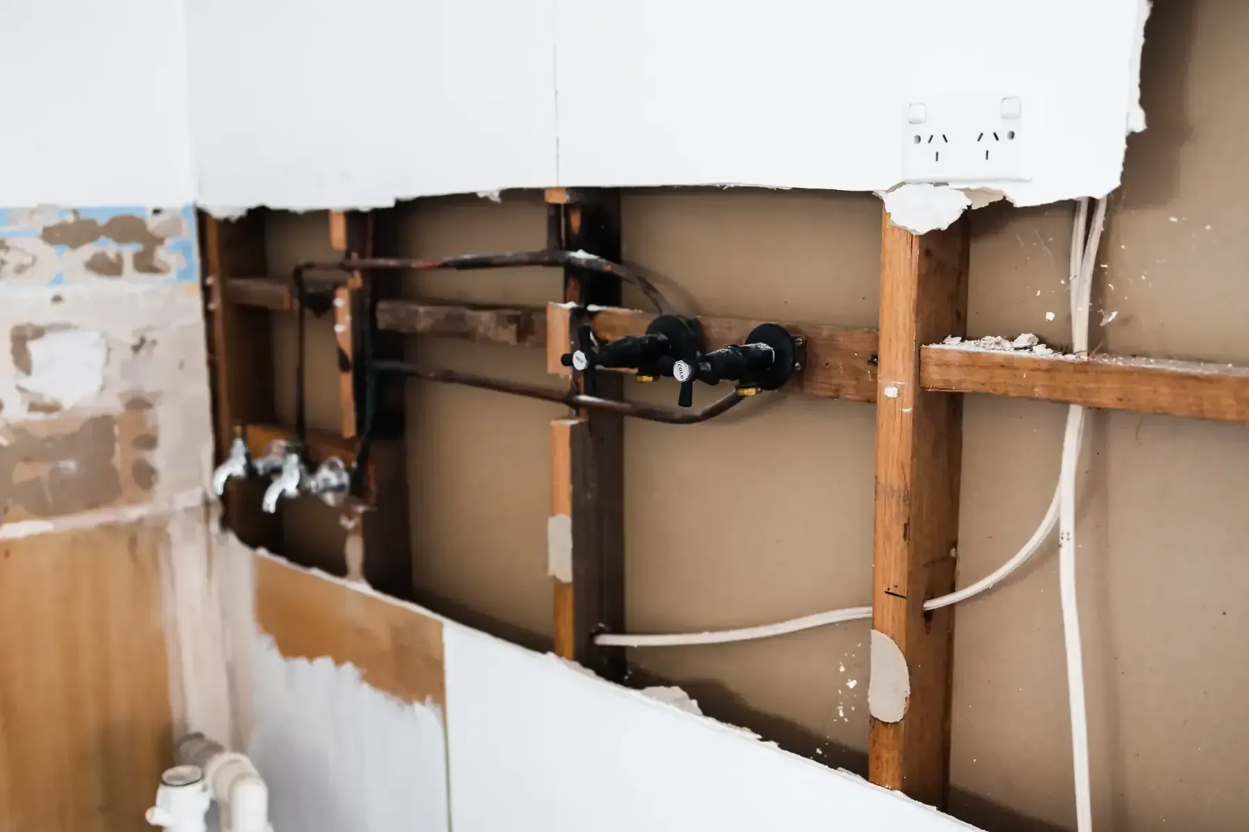 Pared interior durante la renovación, dejando expuestas las tuberías y el cableado eléctrico.