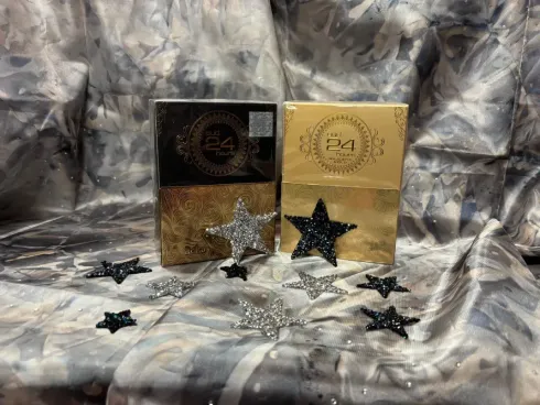Dos productos en caja con decoración de estrellas sobre fondo brillante. Una caja es negra y dorada, la otra dorada.