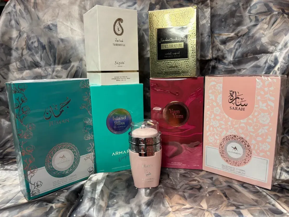 Colección de cajas de perfume de varios colores; un frasco de perfume rosa está al frente.