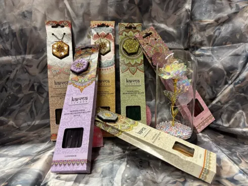 Varitas de incienso surtidas en cajas coloridas y una figurita de rosa en una cúpula transparente.