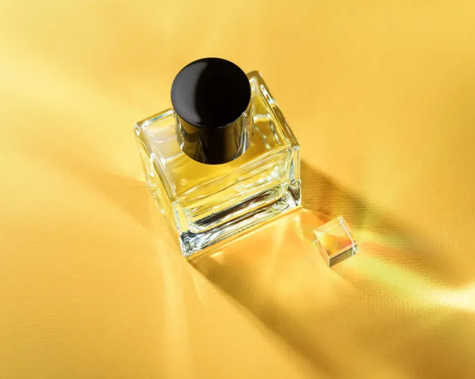 Colección de cajas de perfume de varios colores; un frasco de perfume rosa está al frente.