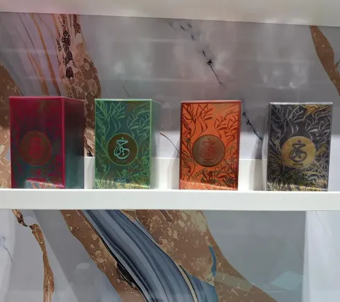 Colección de cajas de perfume en varios colores; algunas doradas, amarillas, naranjas, rosas, negras.