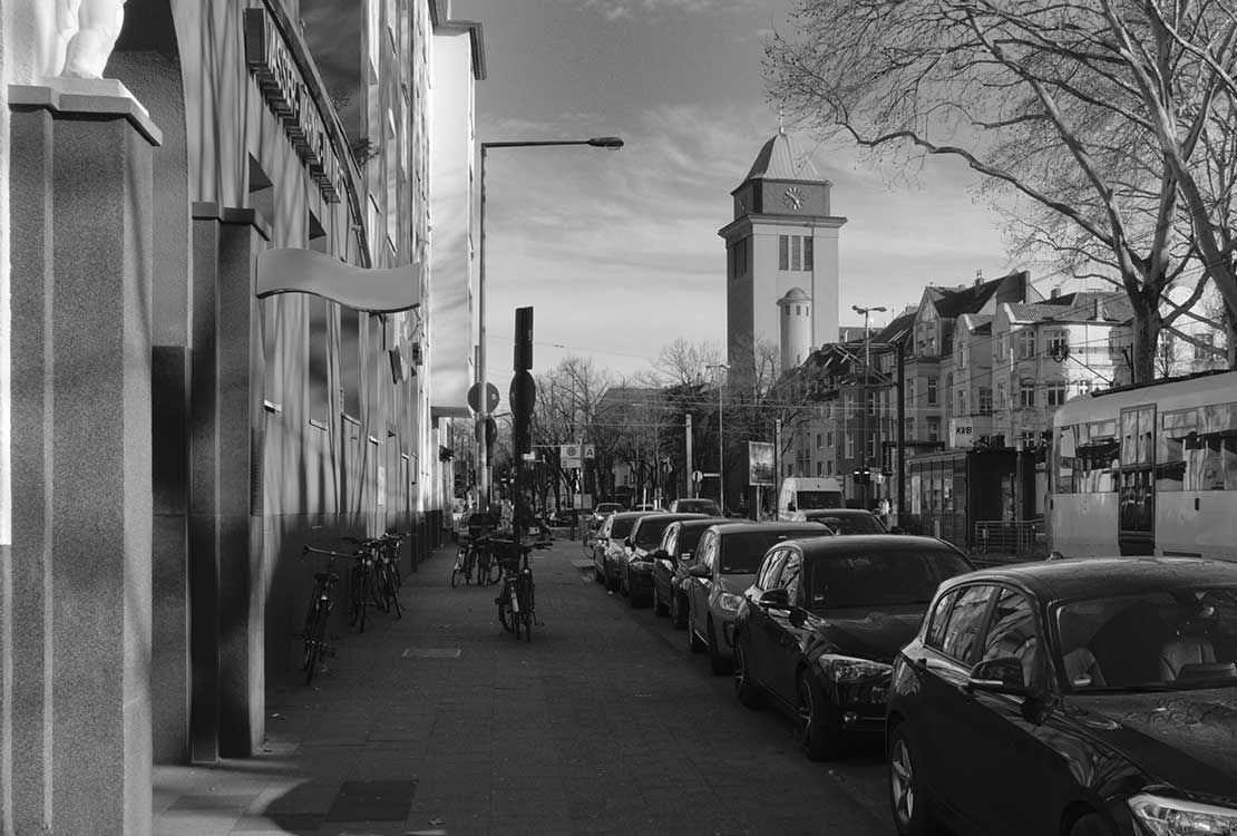 Ein Schwarzweißfoto einer Stadtstraße mit einem Uhrturm im Hintergrund.