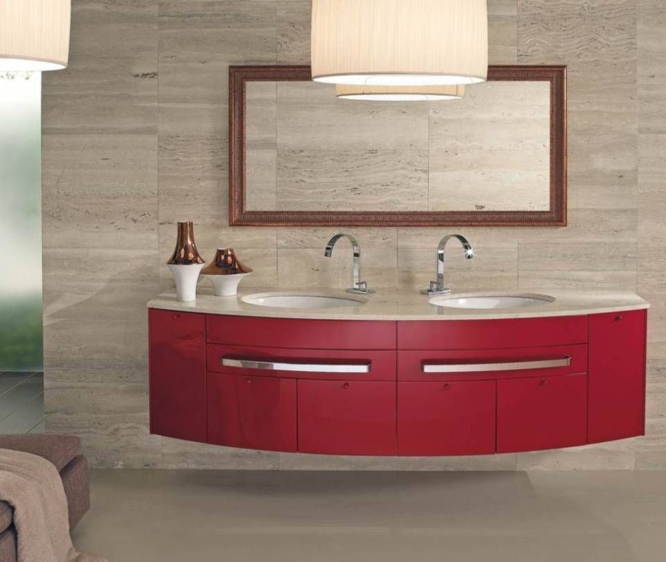 Ein Badezimmerwaschtisch mit zwei Waschbecken, einem glänzend roten, geschwungenen Schrank, einer hellen Steinarbeitsplatte und einem Spiegel mit Holzrahmen.