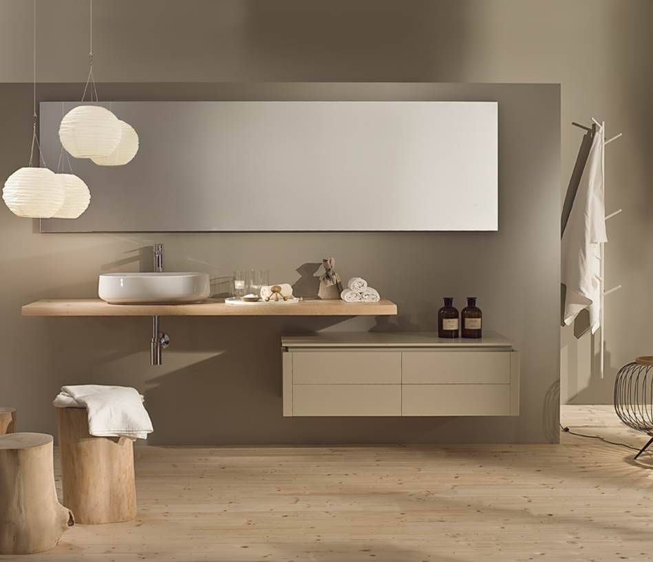 Ein modernes, minimalistisches Badezimmer mit einem schwebenden Waschtisch aus Holz, einem weißen Aufsatzwaschbecken, einem großen Spiegel und hängenden Kugellampen.