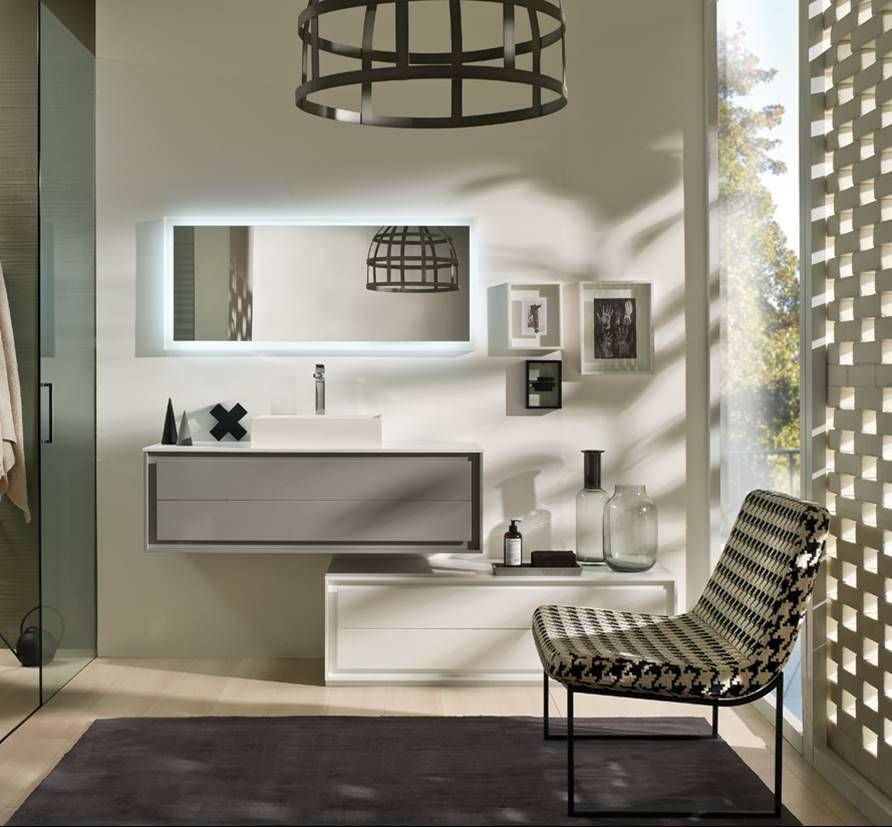 Ein modernes Badezimmer-Waschtisch-Set mit schwebendem Waschbecken, beleuchtetem Spiegel und einem gemusterten Akzentstuhl auf einem dunklen Teppich.