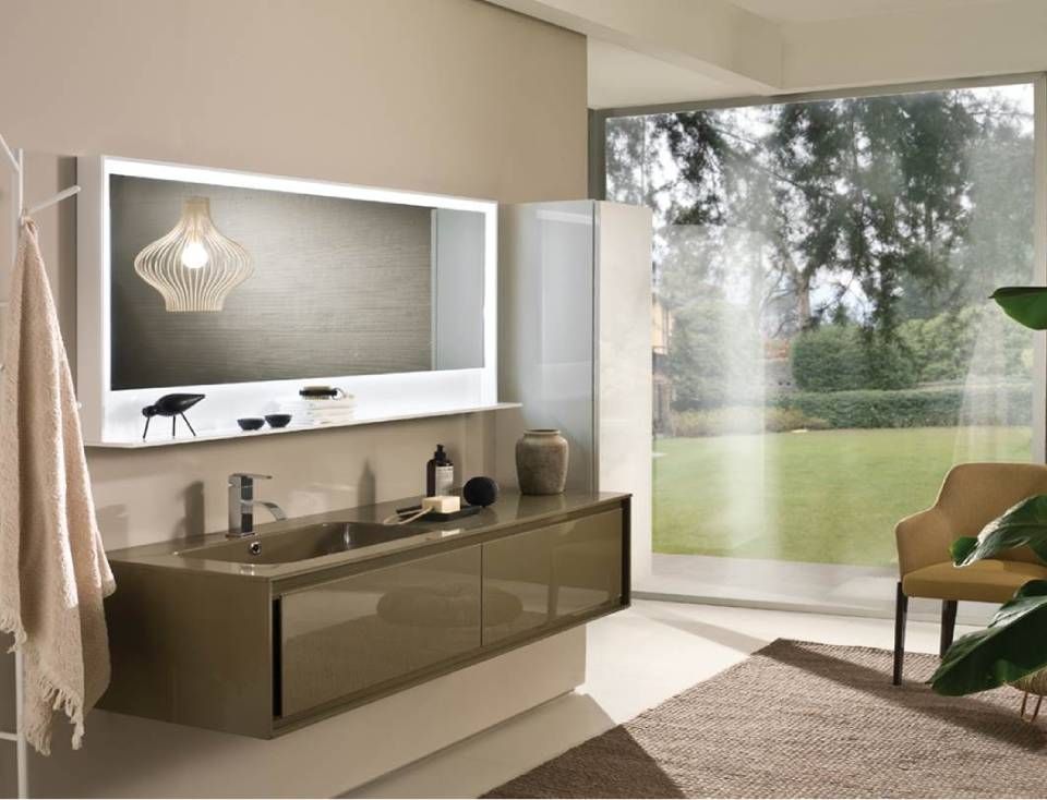 Modernes Badezimmer mit einem langen, taupefarbenen, wandmontierten Waschtisch, einem großen beleuchteten Spiegel und Blick auf einen Garten.