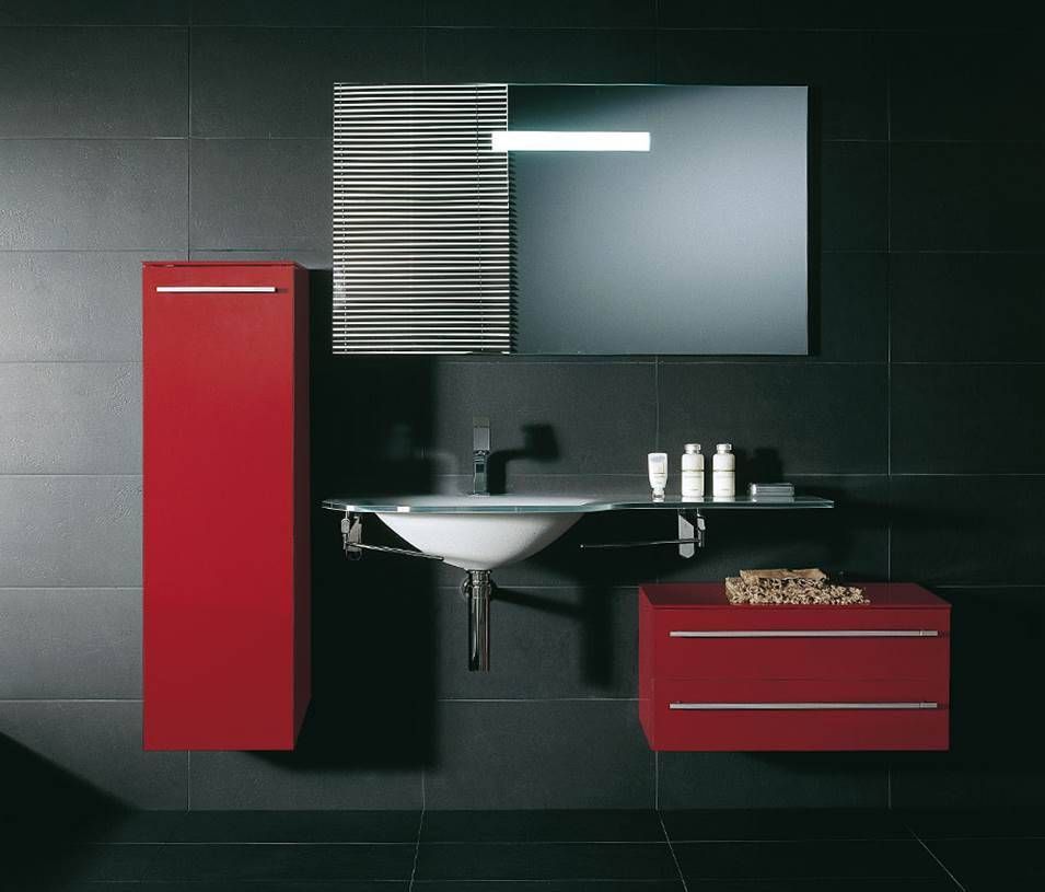 Modernes Badezimmerinterieur mit einem hohen roten Schrank, einem schwebenden roten Waschtisch, einem Waschbecken und einem gestreiften Spiegel vor schwarz gefliesten Wänden.