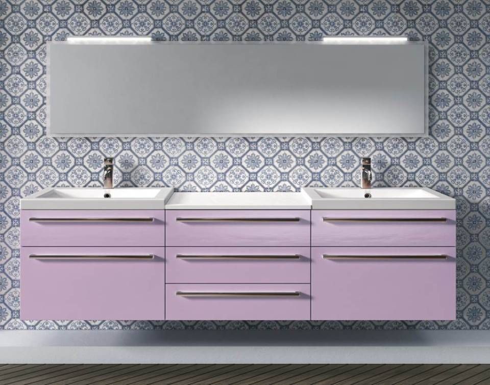 Ein moderner Doppelwaschtisch mit hellvioletten Schubladen und zwei weißen Waschbecken, montiert an einer Wand mit blau gemusterten Fliesen.