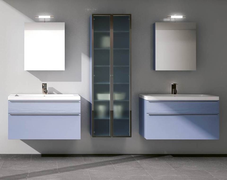 Doppelwaschtisch mit hellblauen, schwebenden Schränken, quadratischen Spiegeln und einem zentralen blauen Glasaufbewahrungsturm vor einer grauen Wand.