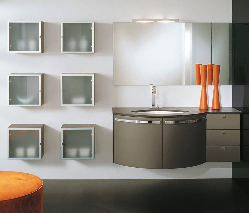 Ein moderner Waschtisch mit geschwungenem Waschbeckenunterschrank, drei Wandschubladen, sechs Milchglasschränken und orangefarbenen Vasen.