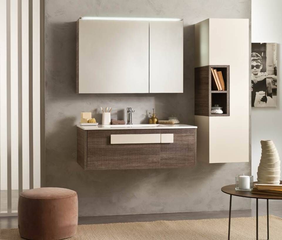 Ein moderner, wandmontierter Waschtisch mit passendem Schrank in Holz- und Cremetönen, mit großem Spiegel und grauer Wand.