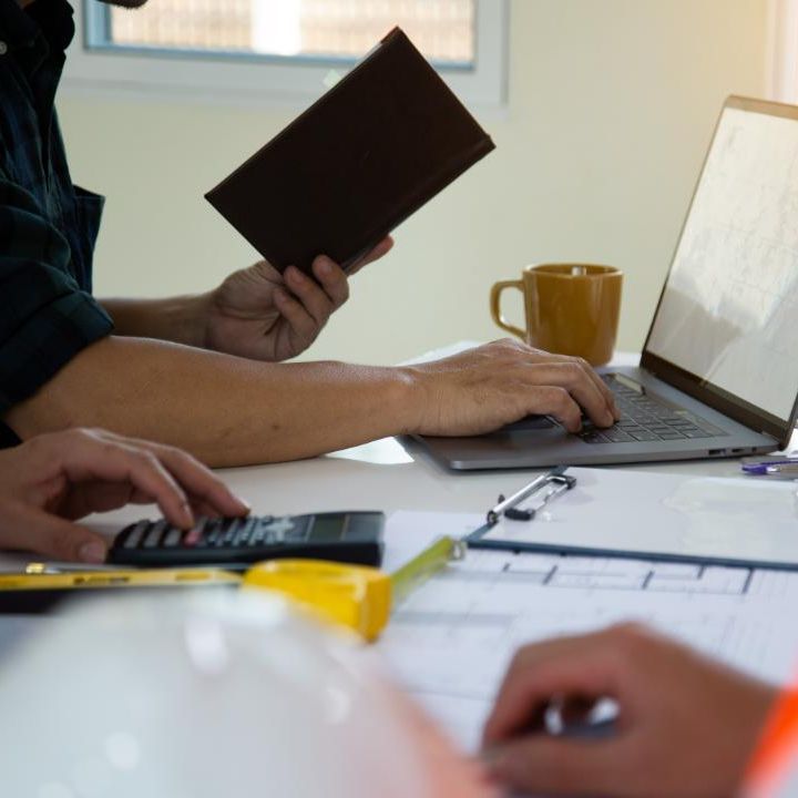 Un hombre sostiene una billetera mientras usa una computadora portátil.