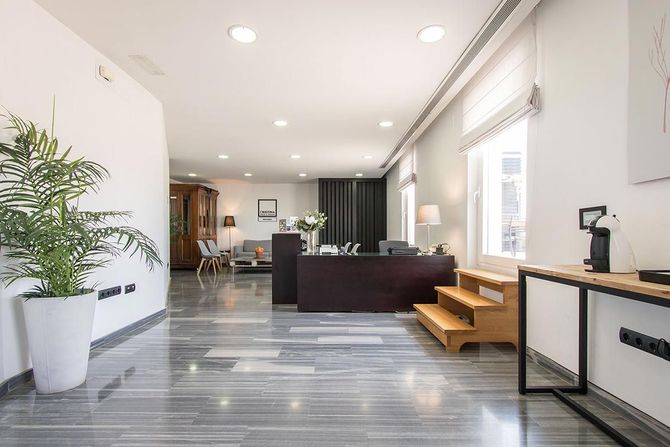 Una sala de estar con un sofá, una mesa, escaleras y una planta en maceta.
