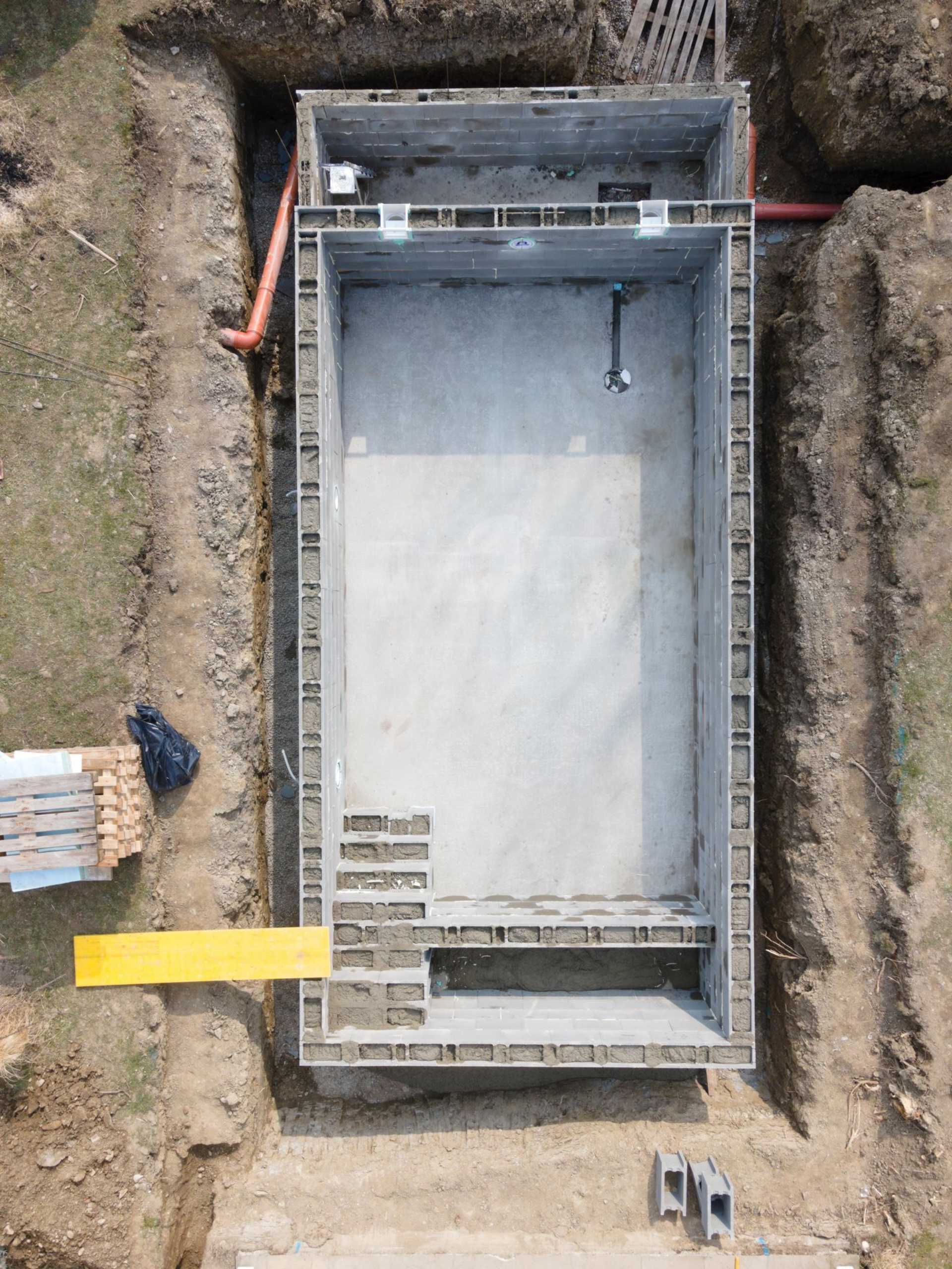 Vue aérienne d'une piscine rectangulaire inachevée en construction sur un chantier de terrassement.