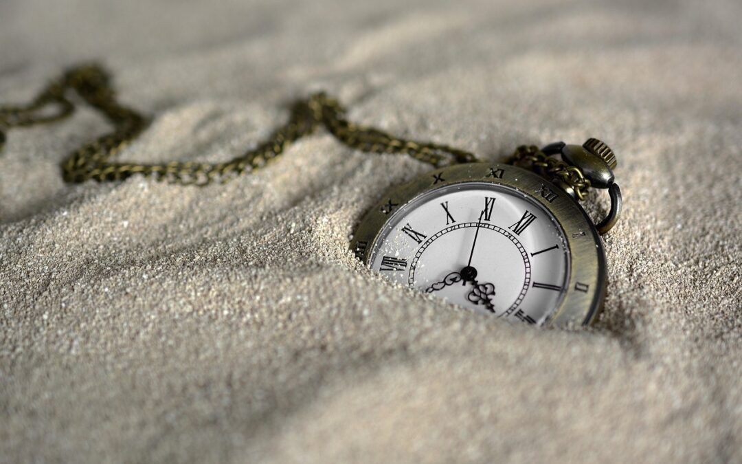 a vintage pocket watch with roman numerals resting in sand, symbolising the idea that autistic women move through life in their own time and space