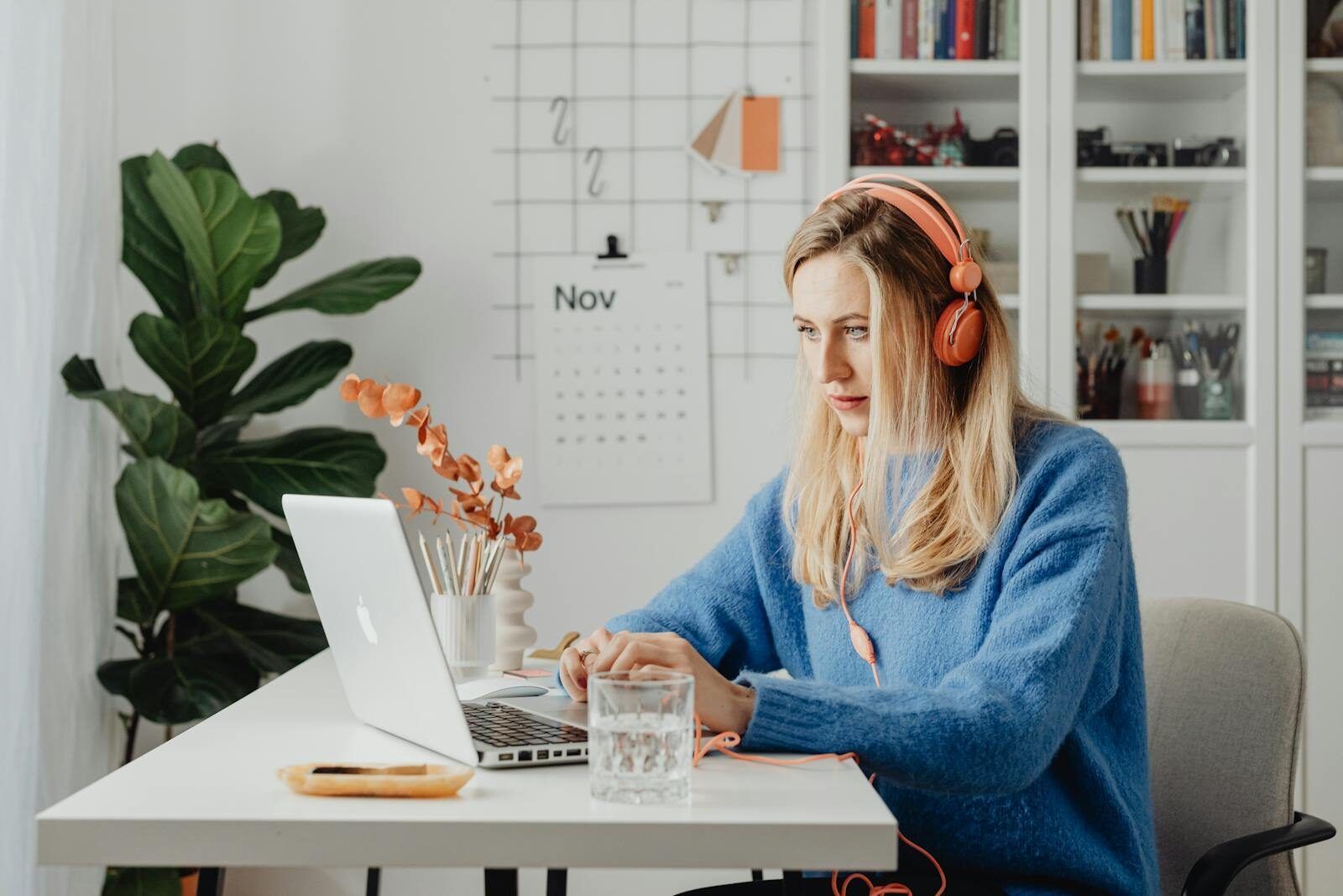 a woman sitting at a bright, organised desk wearing headphones and working focused on her laptop, representing what neurodivergent inclusion in the workplace can look like when environments are designed for different minds
