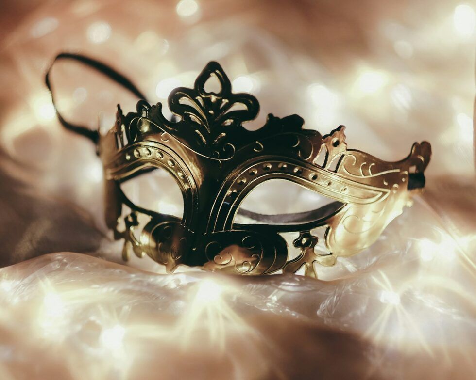 a delicate lace mask resting on golden silk fabric, symbolising the hidden reality of ADHD and autistic masking and the beauty beneath the surface