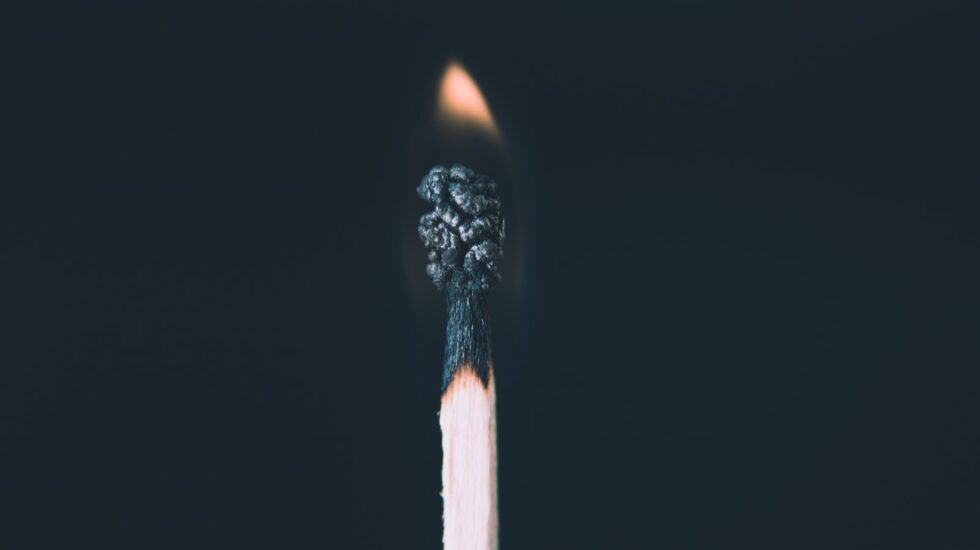 a match with a fading flame against a dark background, symbolising the gradual exhaustion of neurodivergent burnout in women