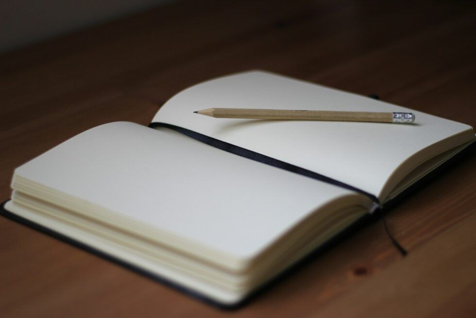 a blank notebook and pen on a wooden table, symbolising the start of an ADHD journey