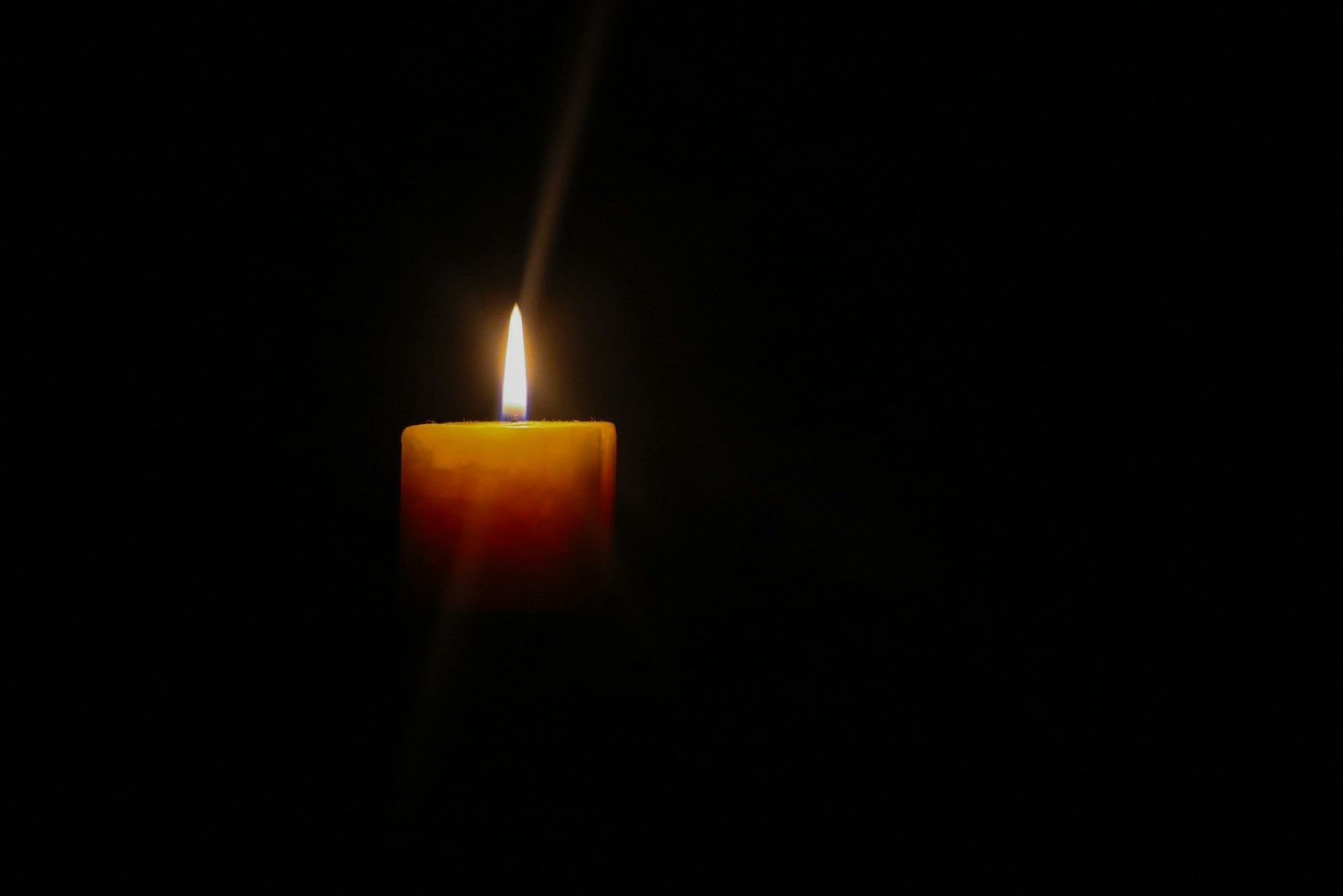 a single lit candle glowing against a dark background, symbolising hope and recovery from neurodivergent burnout in women