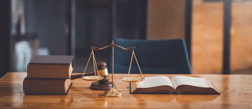 Livres, balance de la justice et marteau sur un bureau en bois.