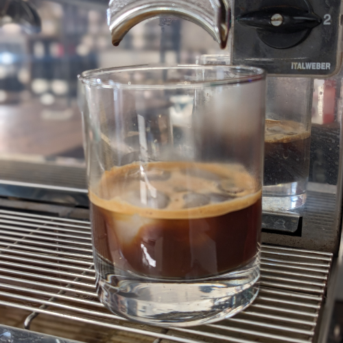 Ein Glas Kaffee wird in eine Kaffeemaschine gegossen.
