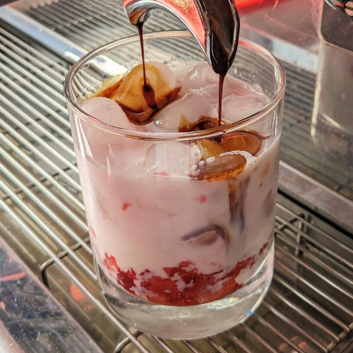 Ein Glas Milch, in das Eis und Schokolade gegossen werden.