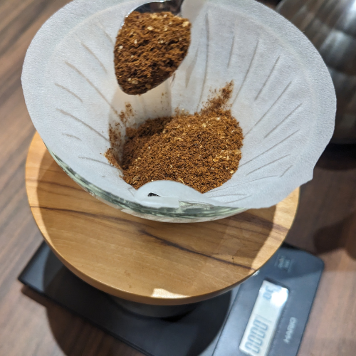 Ein Löffel Kaffee wird in einen Papierfilter gegossen