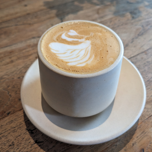 Eine Tasse Cappuccino auf einer Untertasse auf einem Holztisch