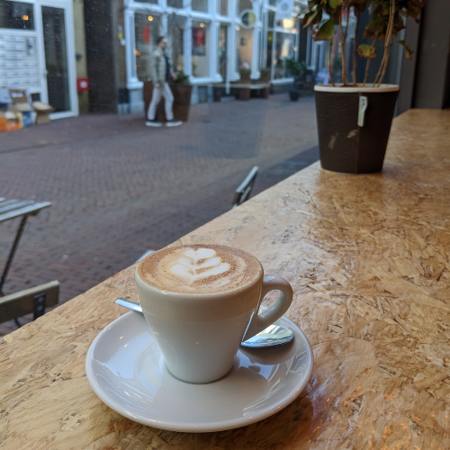 Eine Tasse Cappuccino auf einer Untertasse mit einem Löffel auf einem Holztisch