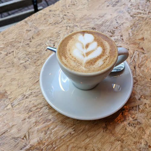 Eine Tasse Cappuccino auf einer Untertasse auf einem Holztisch