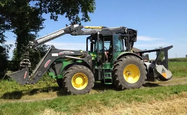 Ein grün-gelber Traktor steht auf einer Wiese.