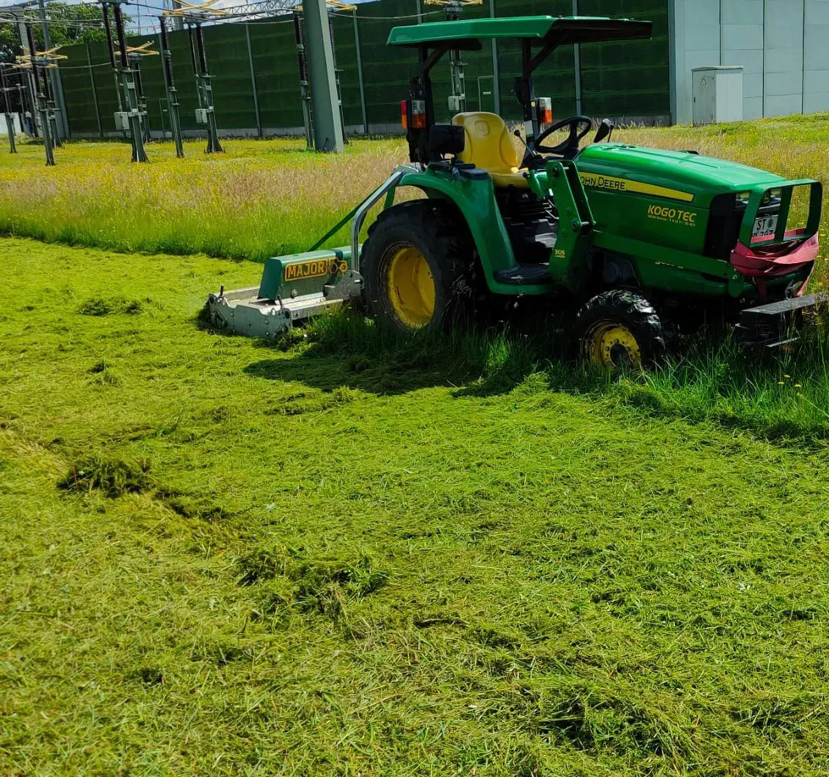 Ein grüner John Deere Traktor mäht ein üppiges grünes Feld