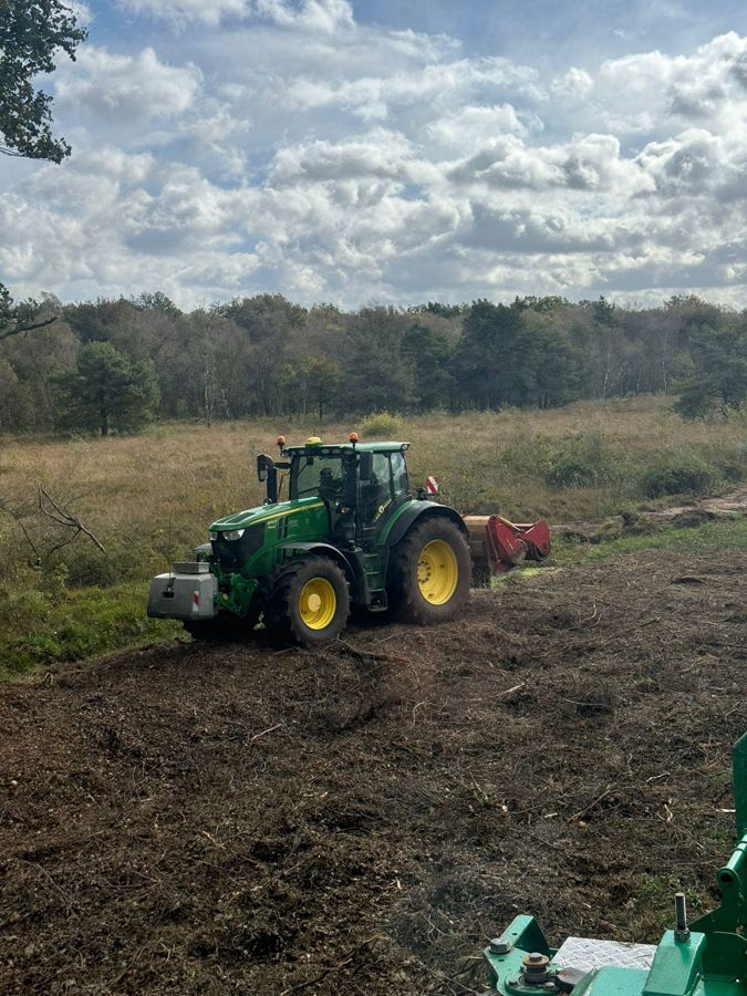Ein grün-gelber Traktor fährt durch ein Feld.