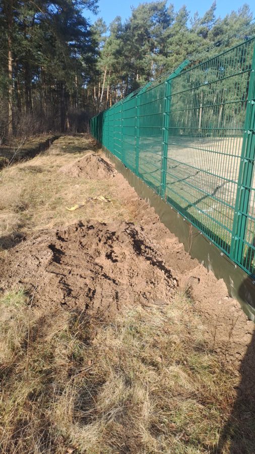 Auf einem Feld ist ein grüner Zaun von Erde umgeben.