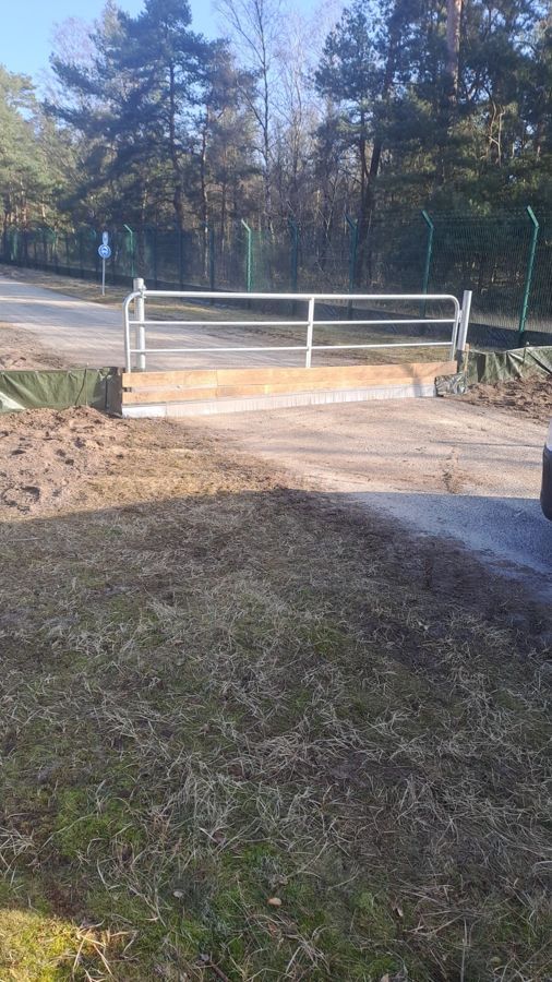 Am Rand einer unbefestigten Straße steht ein weißes Tor.