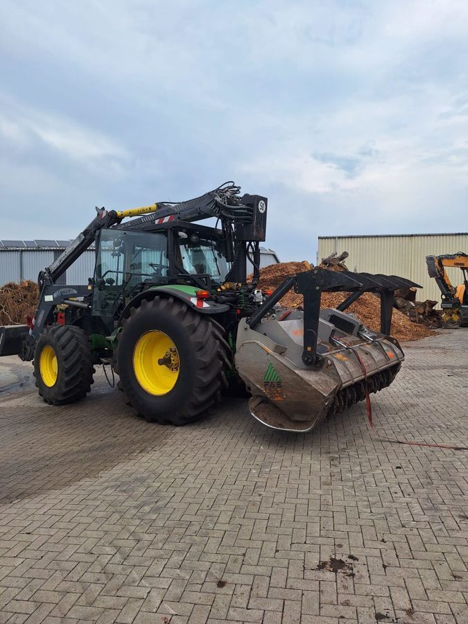 Auf einer gepflasterten Auffahrt steht ein Traktor mit einer daran befestigten Besen.