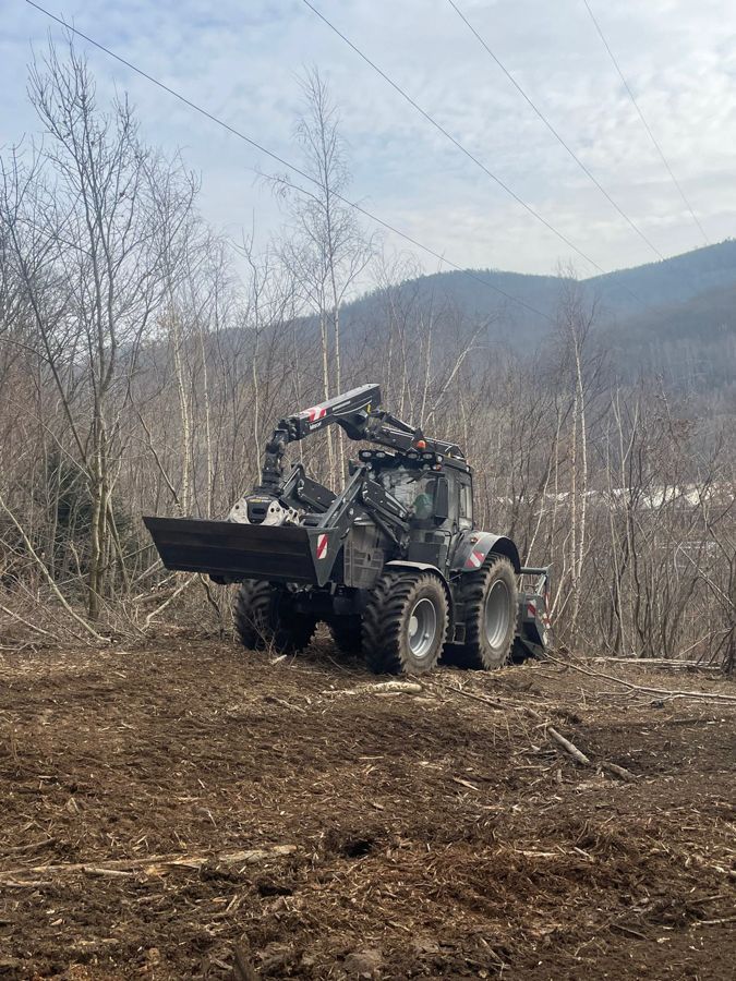 Ein Traktor fährt durch ein Feld mit Bergen im Hintergrund.