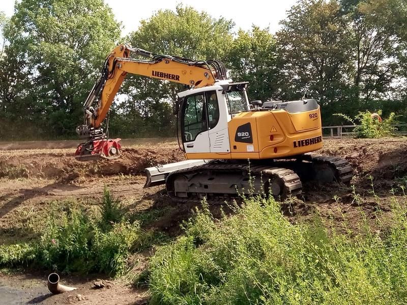 Ein großer gelb-weißer Bagger arbeitet auf einer Baustelle.
