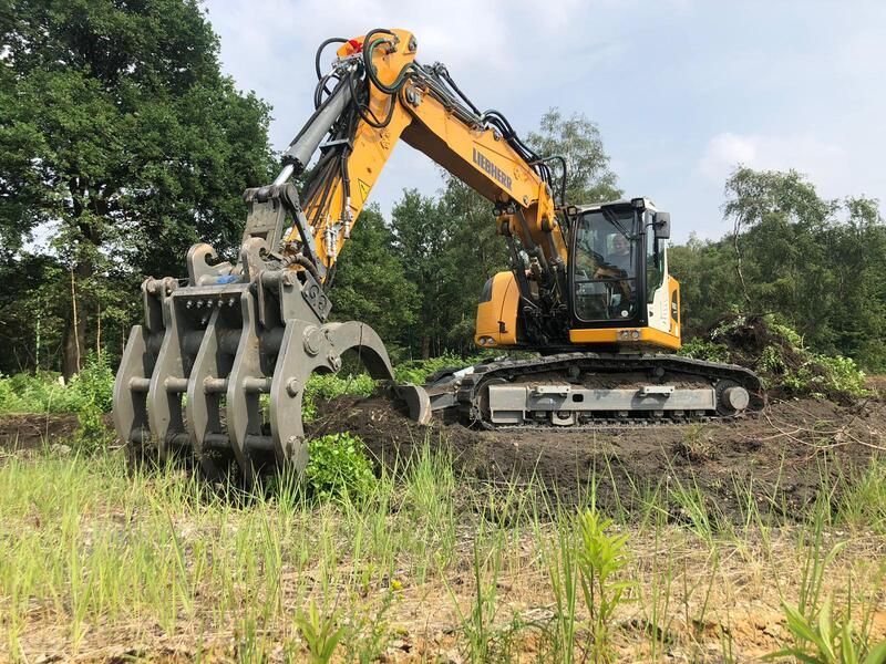 Ein großer Bagger gräbt ein Loch in ein Feld.