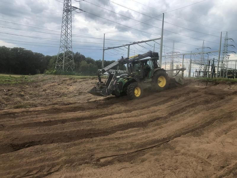 Ein Traktor fährt einen Feldweg entlang.